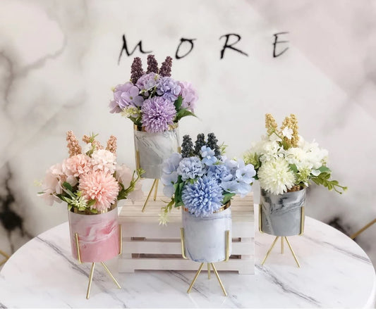 Display for purple, pink, white and blue artificial flower arrangement in ceramic pot.