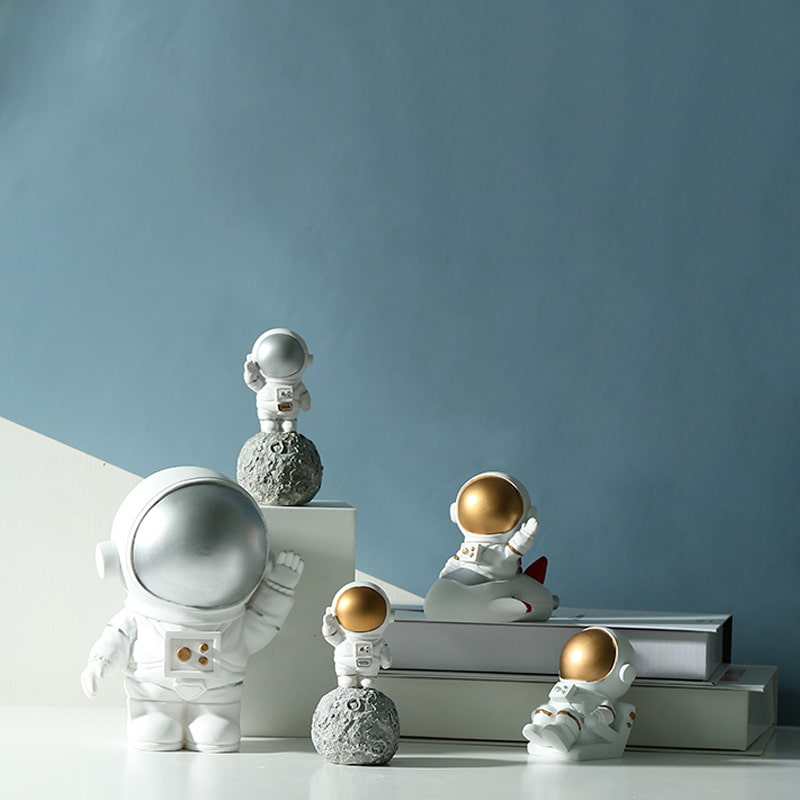 Five different types of astronaut decorations are displayed on the table