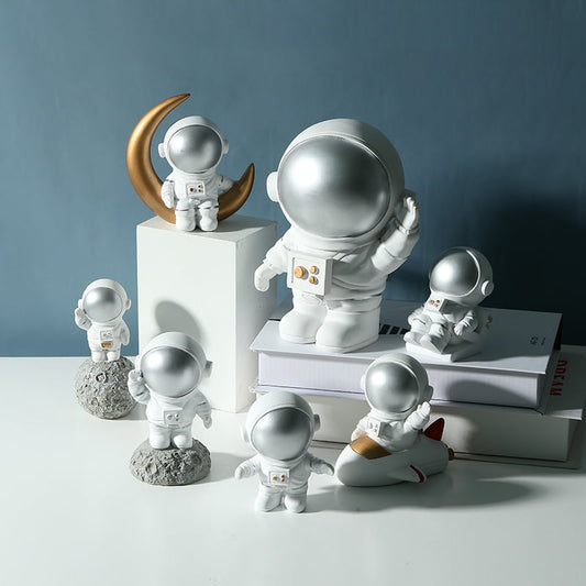 Seven different types of astronaut decorations are displayed on the table.