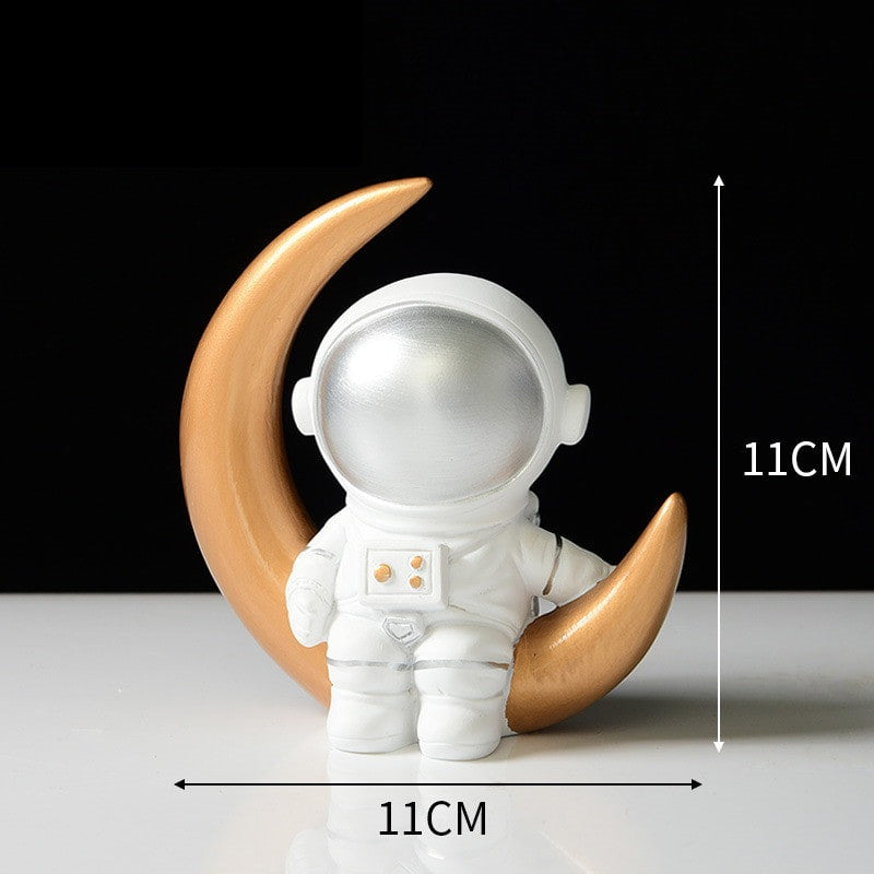 Ornament's style N is an astronaut wearing a silver visor sitting on the gold curved moon.