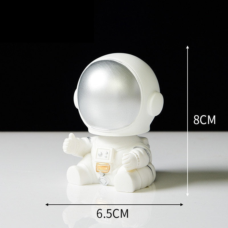 Ornament's style Q is an astronaut wearing a silver visor sitting on the ground with his hands slightly open.