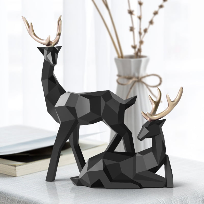 Two geometric deer sculptures in black, one standing and another sitting, displayed on a table.