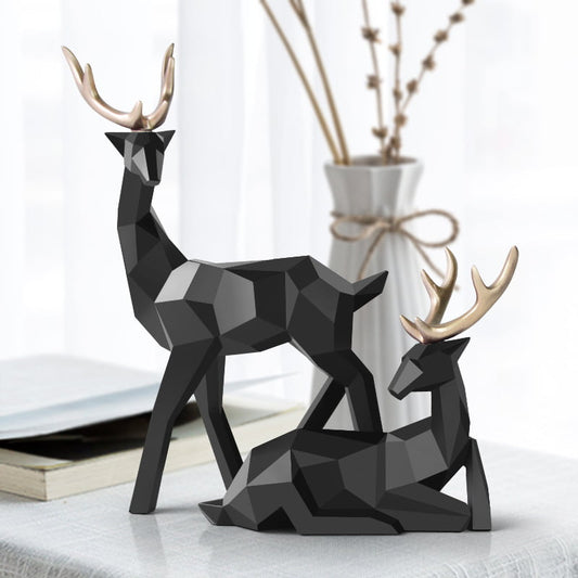 Two geometric deer sculptures in black, one standing and another sitting, displayed on a table.