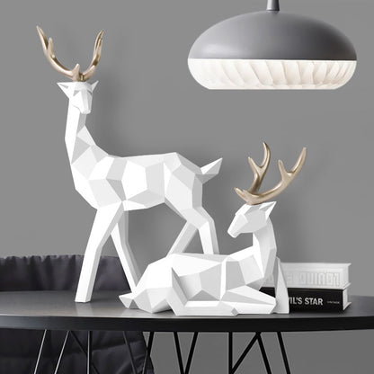 wo geometric deer sculptures in white, one standing and another sitting, displayed on a table.