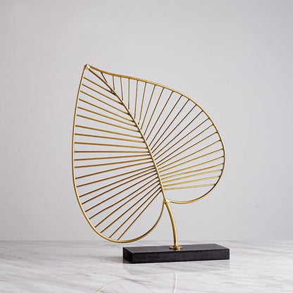 Elegant  gold A-style leaf sculpture on sleek marble table.