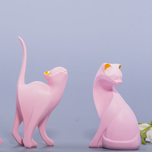 A standing pink cat resin ornament and a sitting pink cat resin ornament are displayed on the table.