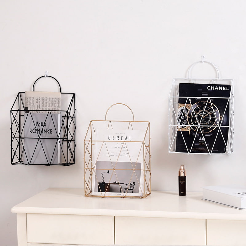 Display for white and black and gold hanging metal magazine holder.