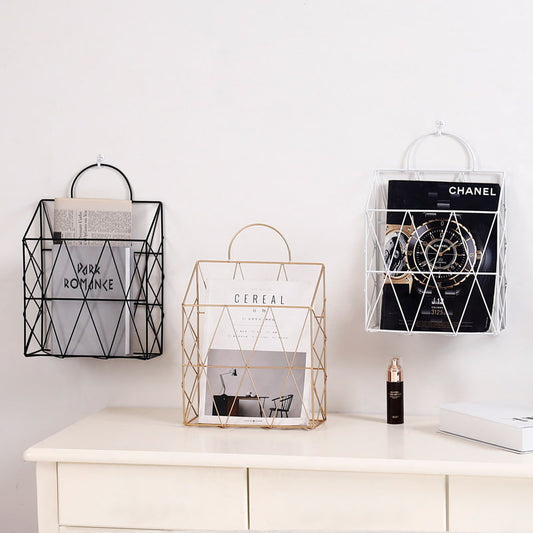Display for white and black and gold hanging metal magazine holder.