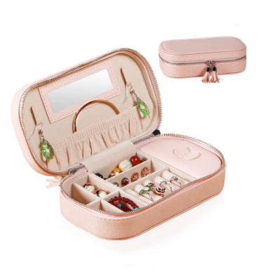 Pink portable jewelry box designed with tassels and zipper closure.